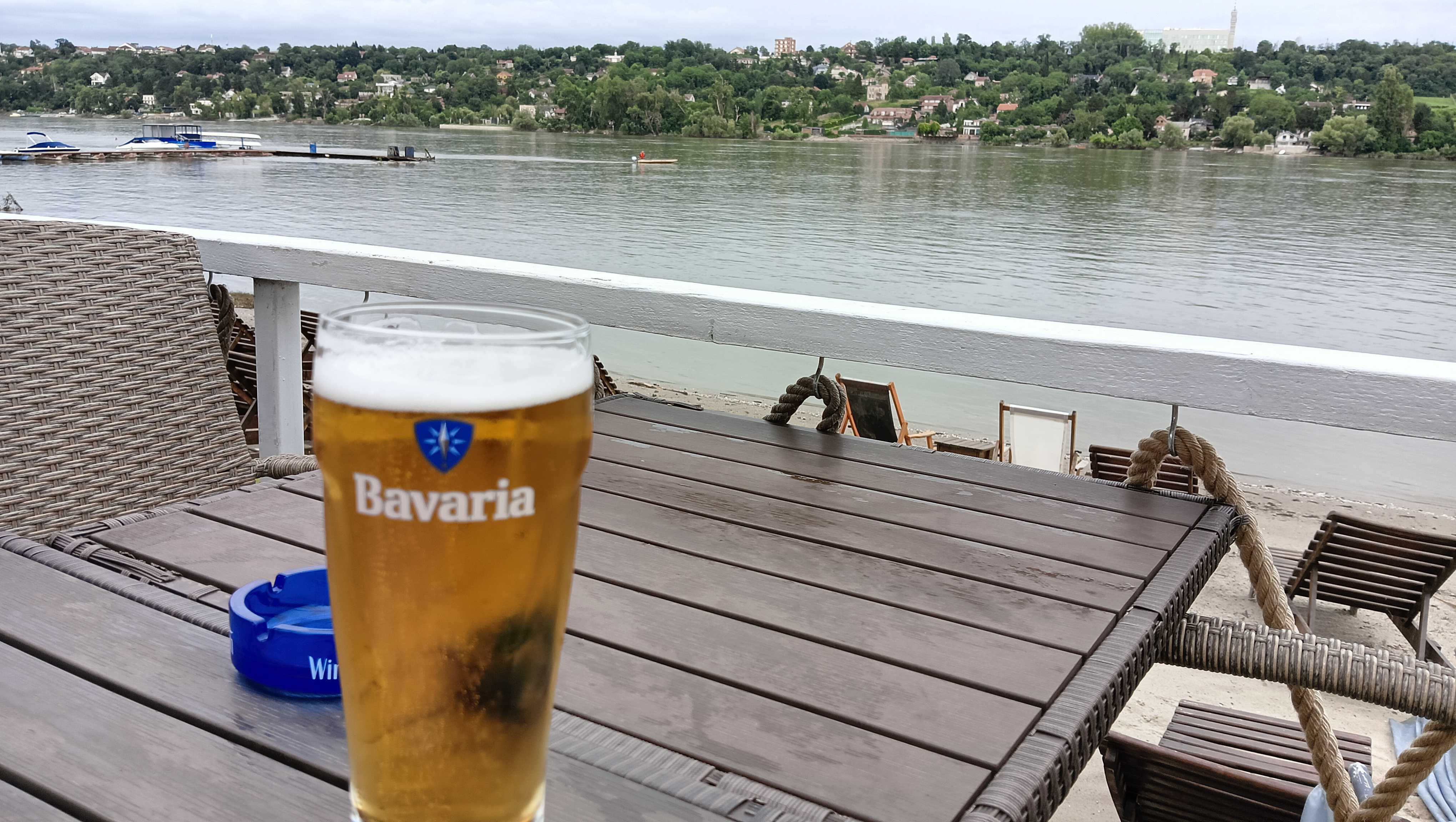 A glass with the beer on the table by the Danube